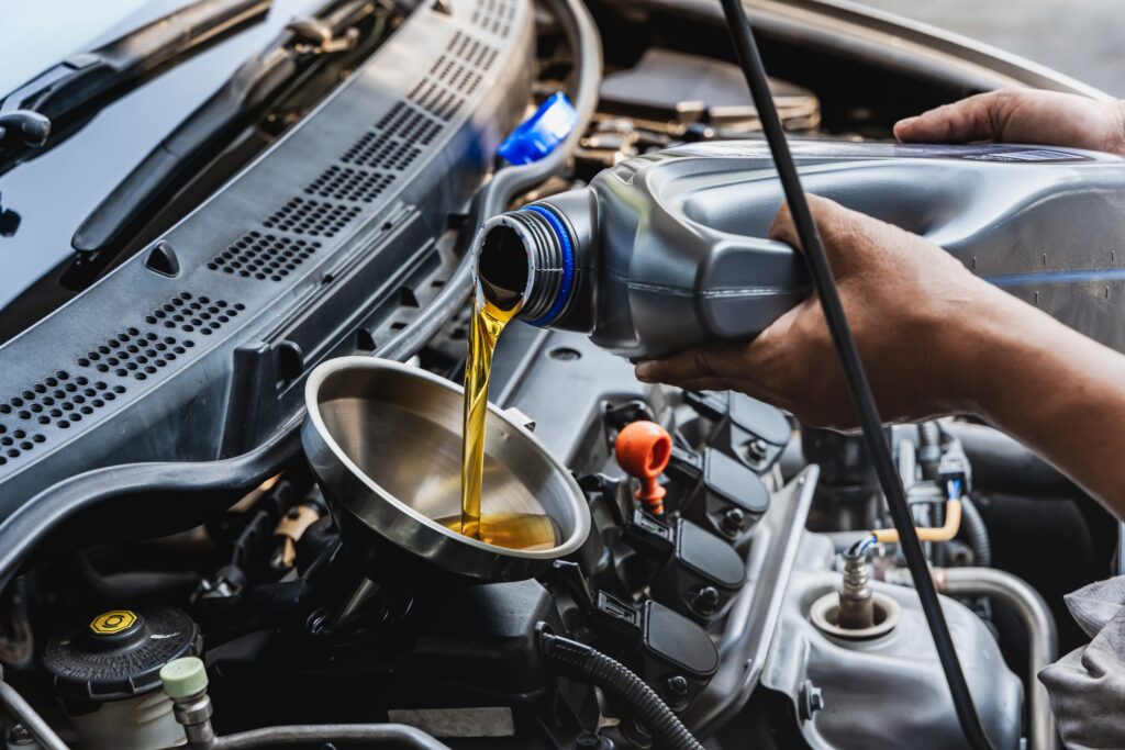 car mechanic pouring engine oil into the vehicle